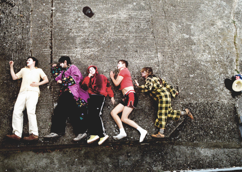 Members of the band 'Sorry' lying down on a concrete floor.x